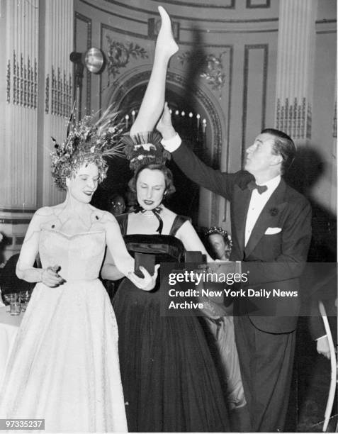 Walter Pidgeon gropes the leg of Mrs. Brooks Howe's headdress, which won the prize for most original headdress at the Bal de Tete in the Plaza Hotel....