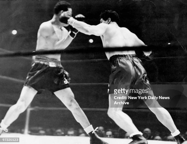 The amazing Chilean, Arturo Godoy , swings a left at Joe Louis in their encounter last night at the Garden, and Joe picks the blow off with his...