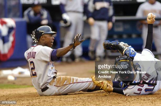 Washington Nationals' Alfonso Soriano signals that he's safe after sliding home as New York Mets' catcher Paul Lo Duca shows the umpire the ball in...