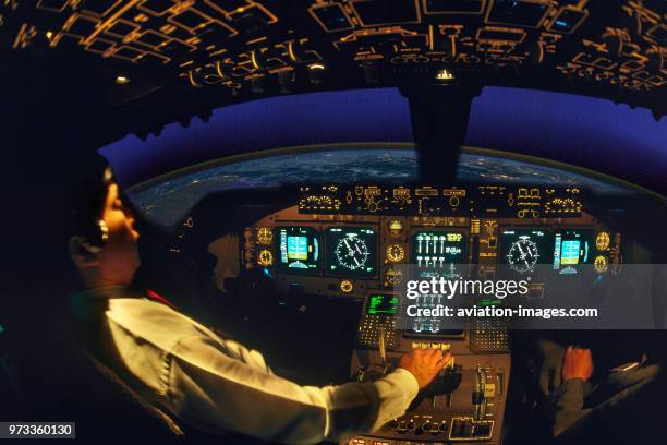 Pilot with hand on the throttle-levers in the Thai Airways International Boeing 747-400 cockpit simulator at high-altitude over Egypt heading north...