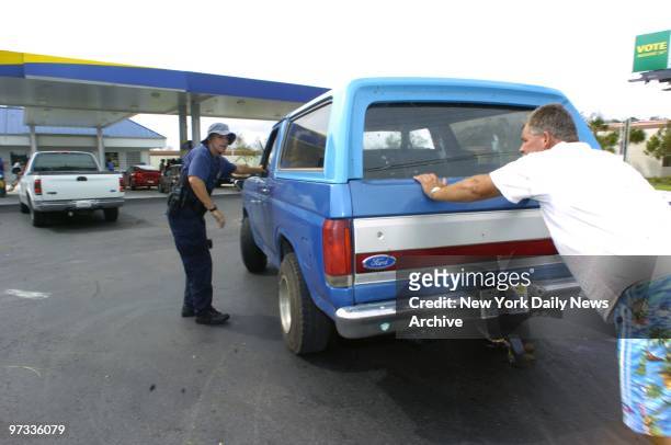Out of gas, Randy Adam supplies manpower to get his SUV to a pump at one of the few open stations in Fort Pierce after Hurricane Frances walloped...