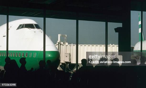 Passengers in the departure-lounge with a Cathay Pacific Airways Boeing 747-200 parked with jetway behind.