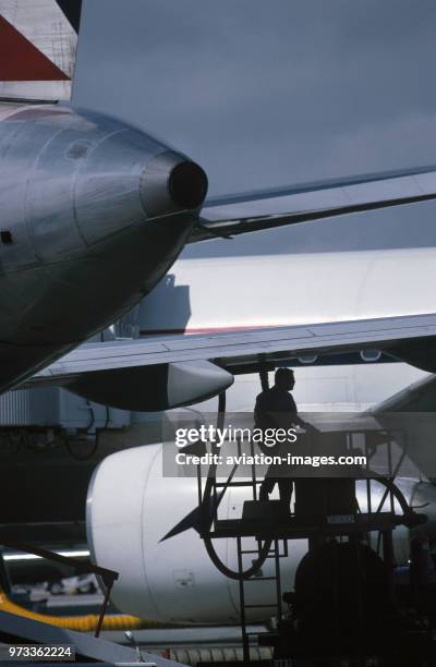 Refueller with a fuel-hose attached to the underside of the wing of a Boeing 767-200 parked and an APU exhaust outlet.