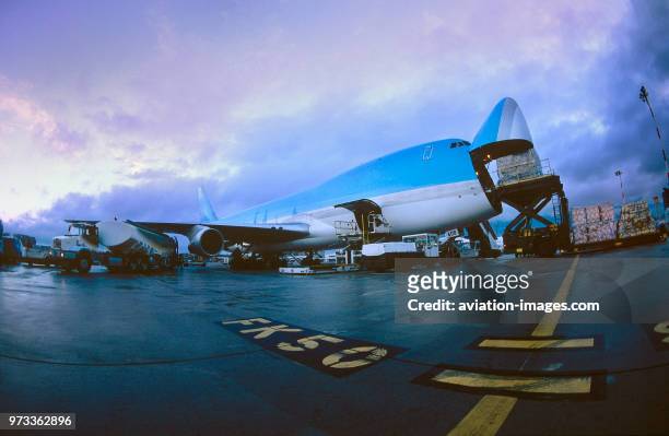 Cargo being loaded through the nose cargo door of a Boeing 747-200F freighter at dawn.