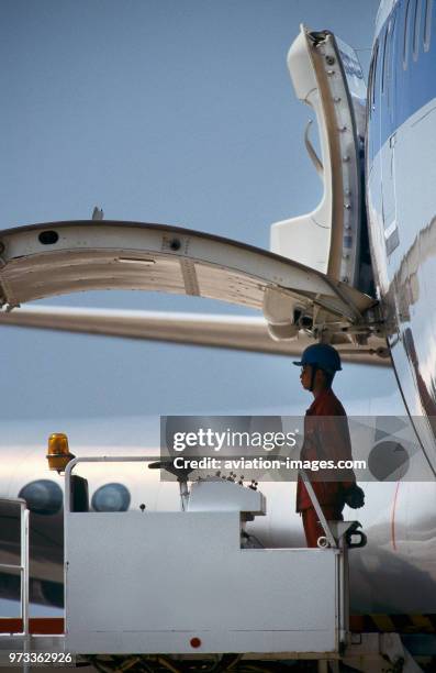 Man standing waiting to start loading cargo next to open side cargo door of a Boeing 747-200.
