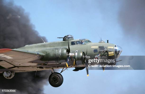 Boeing B-17G Flying Fortress named 'Texas Raiders' taking-off through a cloud of black smoke with undercarriage retracting in the flying-display at...