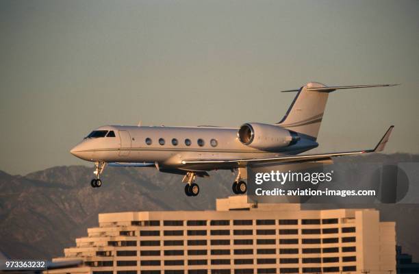 Gulfstream 400 on final-approach with flaps deployed and a hotel behind.