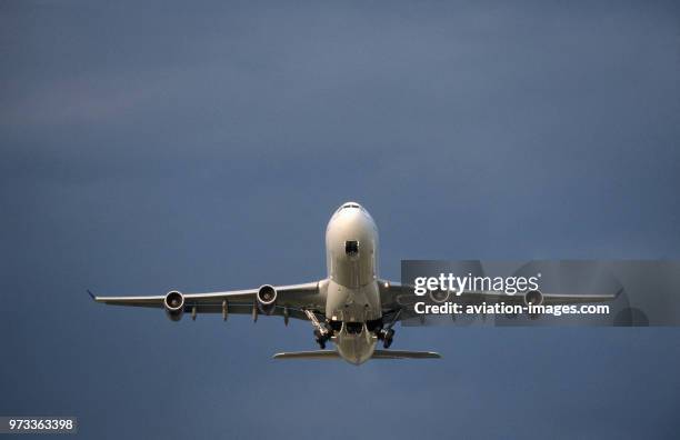 EgyptAir Airbus A340-200 climbing out after take-off with undercarriage retracting with dark clouds behind.