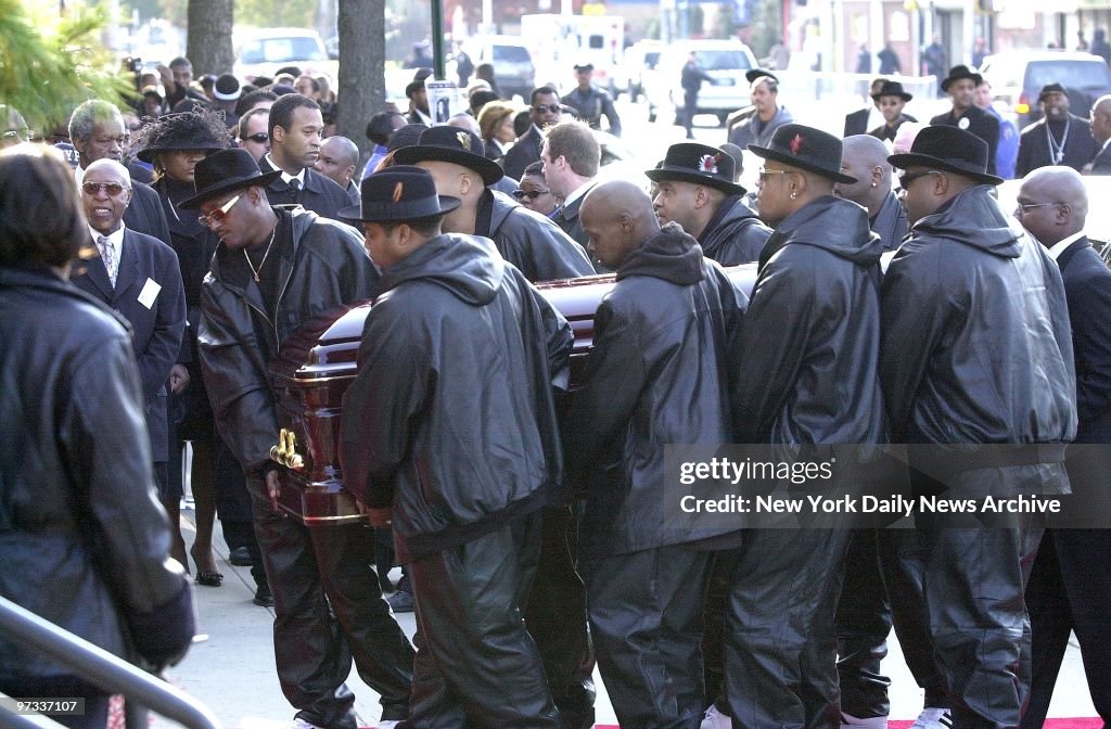Pallbearers wearing trademark fedoras carry coffin of slain 