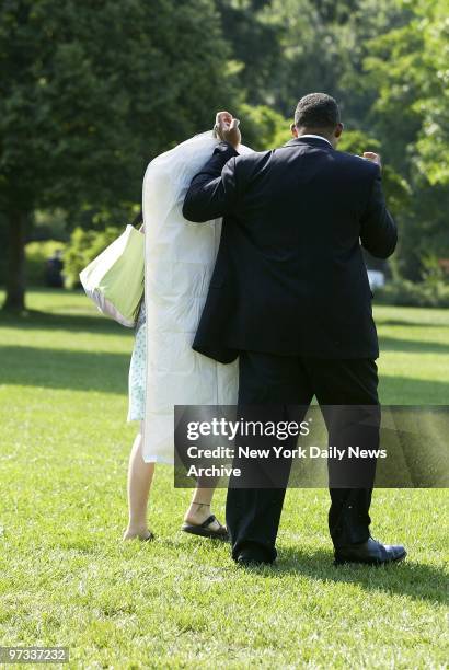 White House valet holds up garment bags to shield Jenna Bush from the media as she walks across the White House lawn to board Marine One for a...