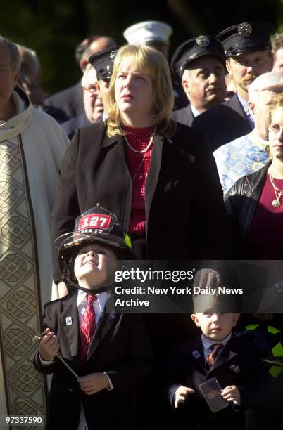 Widow Yetta O'Shea stands with sons Matt and Jake who is wearing his father's fire helmet, outside the Good Shepherd Catholic Church in Holbrook,...