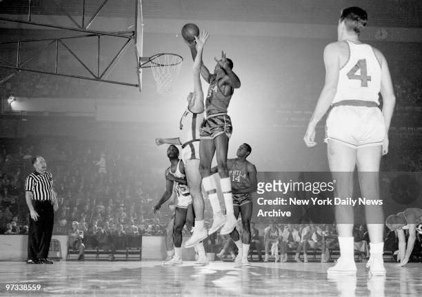 Wilt Chamberlain, Philadelphia's sensational rookie, lays one up and in despite defensive efforts of Knicks' Charlie Tyra in first period at Garden....