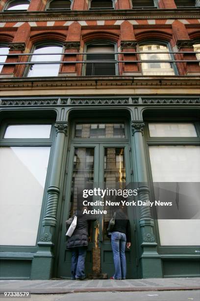 Passersby look through the door of the Prada flagship store at 575 Broadway after a five-alarm fire ripped through the SoHo building last night. The...