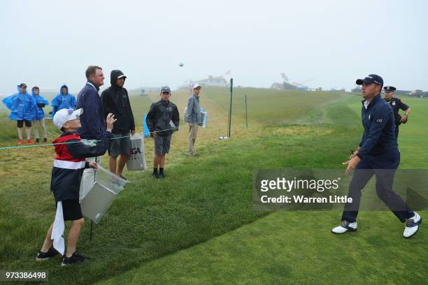 Justin Thomas of the United States throws an autographed golf ball to a junior fan during a practice round prior to the 2018 U.S. Open at Shinnecock...