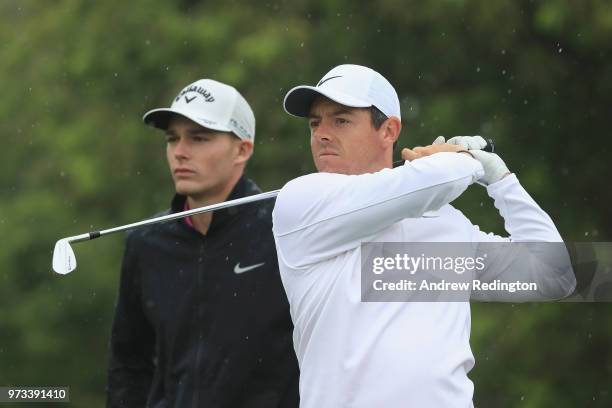 Rory McIlroy of Northern Ireland hit a shot as Aaron Wise of the United States looks on during a practice round prior to the 2018 U.S. Open at...