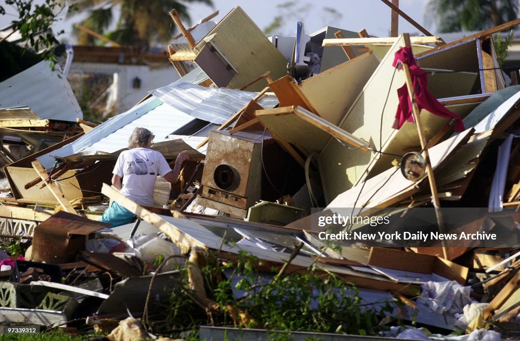 Woman looks through the wreckage of her home in a trailer pa