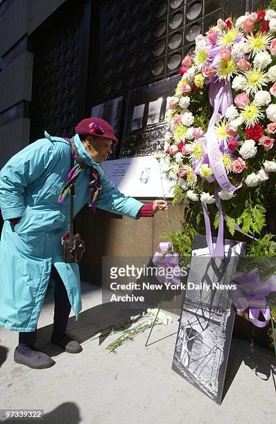 Woman places flowers next to wreath at the site of the Triangle Shirtwaist Factory fire that killed 146 garment workers, mostly women and young...