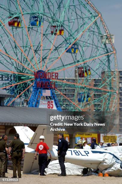 Wonder Wheel towers in the background as emergency crews investigate the scene of a small plane crash on the beach at W. 16th St. On Coney Island....