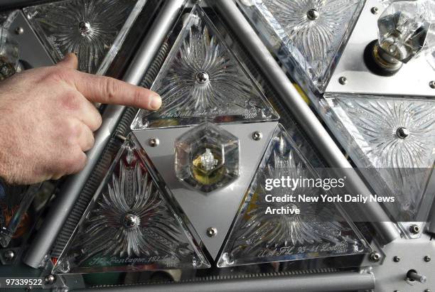 Worker points out details of the exterior of the Times Square New Year's Eve ball. This group of three Waterford crystal triangles contains one...