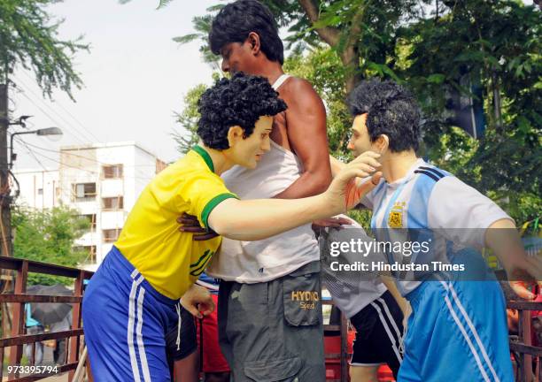 Idol makers carry idols of some of the icon footballers like Messi, Neimar and Ronaldo and a replica of World Cup to a fan club at Baghajatin, on...