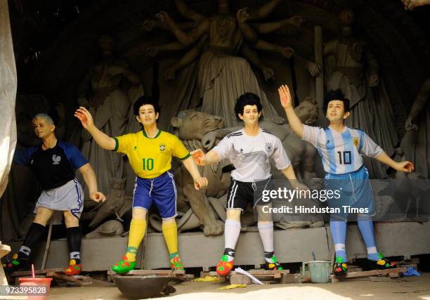 Idol makers carry idols of some of the icon footballers like Messi, Neimar and Ronaldo and a replica of World Cup to a fan club at Baghajatin, on...