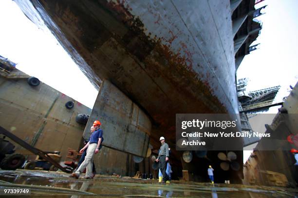 Workers walk under the keel of the World War 2 era aircraft carrier Intrepid as it sits in dry dock at Bayonne Dry Dock & Repair Corp. On the...