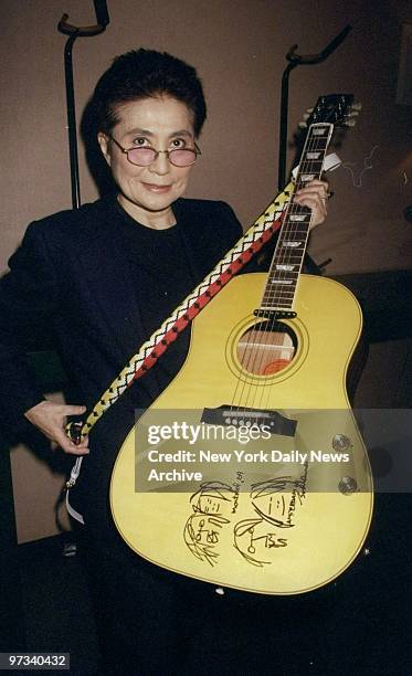 Yoko Ono holds a Gibson replica of a John Lennon guitar at the BMI Foundation.