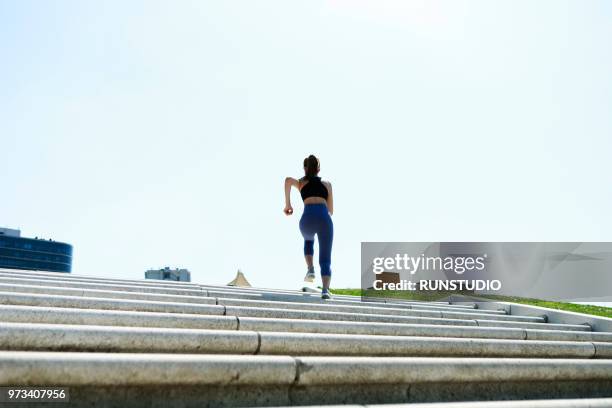 sporty young woman running up staircase - 上昇 ストックフォトと画像