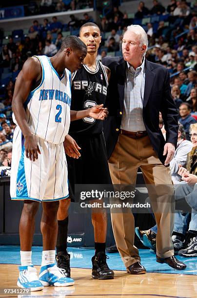 Darren Collison of the New Orleans Hornets attempts to listen in to a conversation between George Hill of the San Antonio Spurs and head coach Gregg...