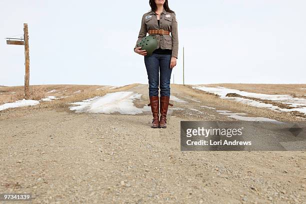 woman in army inspired clothing on dirt road - lori andrews stock pictures, royalty-free photos & images