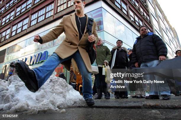 Pedestrians traverse a deep, slushy puddle at the corner of Broadway and 14th St. In Manhattan the day after New York was buried under a record 26.9...
