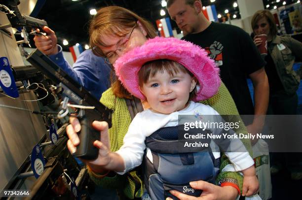 Peggy Irving from Missouri lets her 16-month-old daughter, Katie, hold a gun at a Smith & Wesson display during the National Rifle Association's...