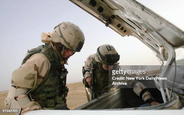 Pennsylvania National Guardsmen Andrew Taylor and Tim Byers check for bombs in an Iraqi car in Tikrit on the eve of Iraq's national election.