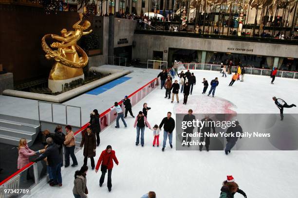 People enjoy a late fall afternoon at the Rockefeller Center ice skating rink.