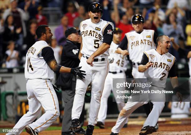 Pittsburgh Pirates' second baseman Jose Castillo , shortstop Jack Wilson and other players rush in to celebrate as third baseman Joe Randa crosses...