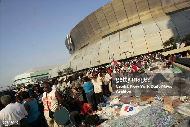 People stand next to piles of garbage outside the Superdome in New Orleans as they wait to be evacuated from the city in the wake of Hurricane...