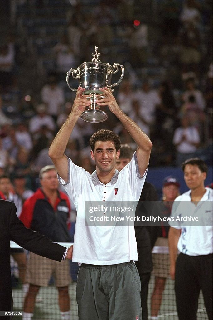 Pete Sampras raising trophy above his head after defeating M