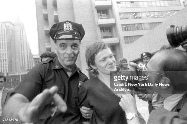Philippe Petit answers reporter's questions as he is escorted from Beekman Hospital by Port Authority police officer. Petit was arrested after he...