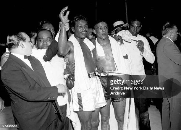 Plenty to Smile About. Sugar Ray Robinson smiles as his right hand is held aloft in championship tradition and his left arm consolingly lies across...