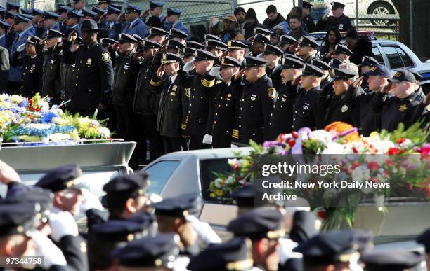 Police officers salute as hearse passes by carrying coffin of Jersey City Police Officer Shawn Carson outside Mount Olive Baptist Church in Jersey...