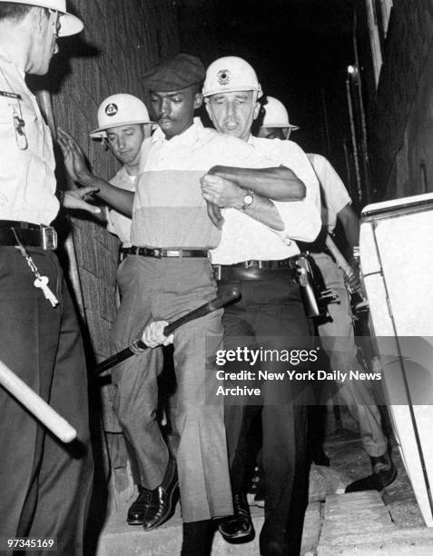 Police in riot gear capture a man suspected of throwing Molotov cocktails during racial riots in the city.