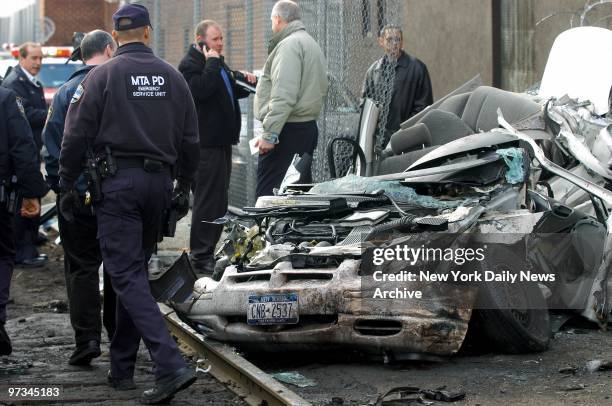 Police investigate near a crushed auto at 55th St., Queens, after it was hit by a runaway locomotive. An unmanned locomotive broke loose during a...