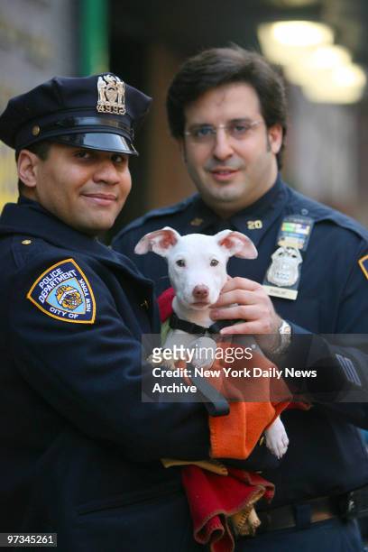 Police officer Andrew Dorsett and Sgt. Rick Khalaf hold a 5-month-old pit bull terrier mix that was rescued after being tossed down a garbage chute...