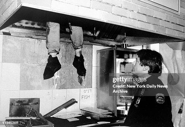 Police Officer Bill Hintz looks at the legs of a perpetrator who suffocated after getting stuck in a grill exhaust chimney duct.