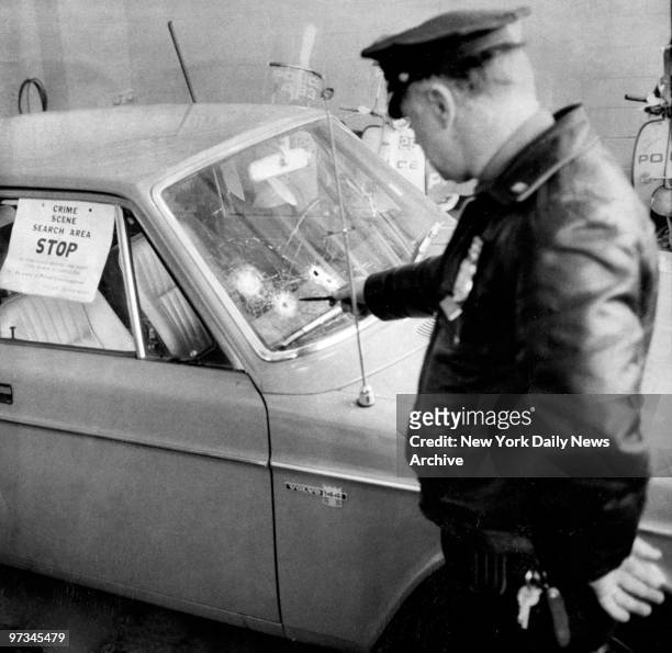 Police officer looks at bullet riddled car that Court Officer Albert Gelb was driving home last night. Gelb was found dead at the wheel