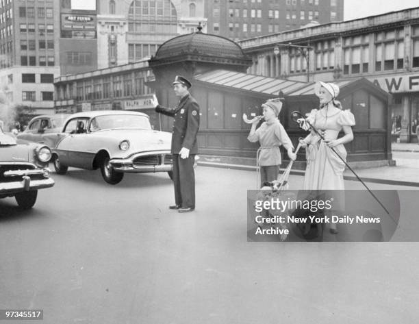 Police Officer Ruben Kasten holds up traffic to permit Little Boy Blue and Little Bo Peep and their lambs to cross to the Coliseum at 59th St. And...