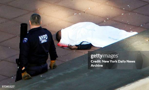 Police officer stands watch over a body on the sixth-floor ledge of the Empire State Building after a man scaled a 10-foot fence and leaped to his...