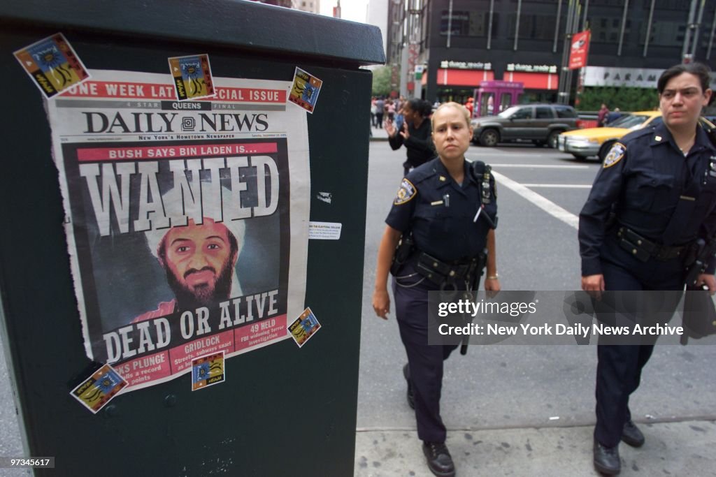 Police officers pass a Daily News cover showing a picture of