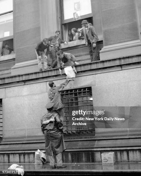 Policeman watches student pass food for besieged Columbia University officials who were barricaded in Columbia University President Grayson Kirk's...