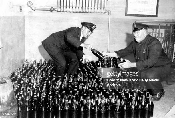 Policemen Goldinger and Faulkner check over 500 bottles of home brew seized in Rockaway Beach speakeasy raid by men from the 15th Inspection District.